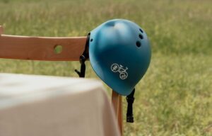 Blue bike helmet perched on the back of a wooden chair.